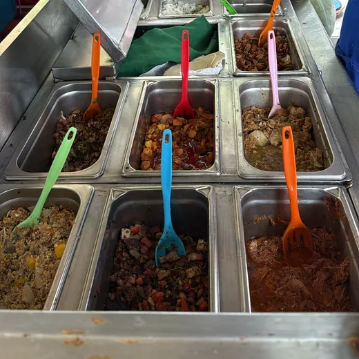 Las charolas de los guisos en el carrito, cada una con su cuchara