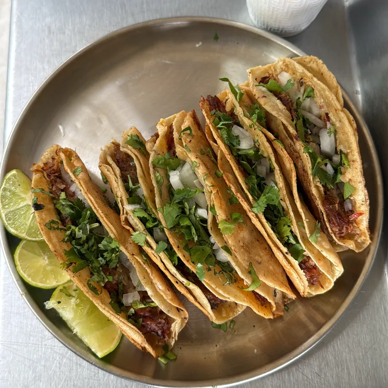 Tacos dorados de birria con cilantro, cebolla y limón